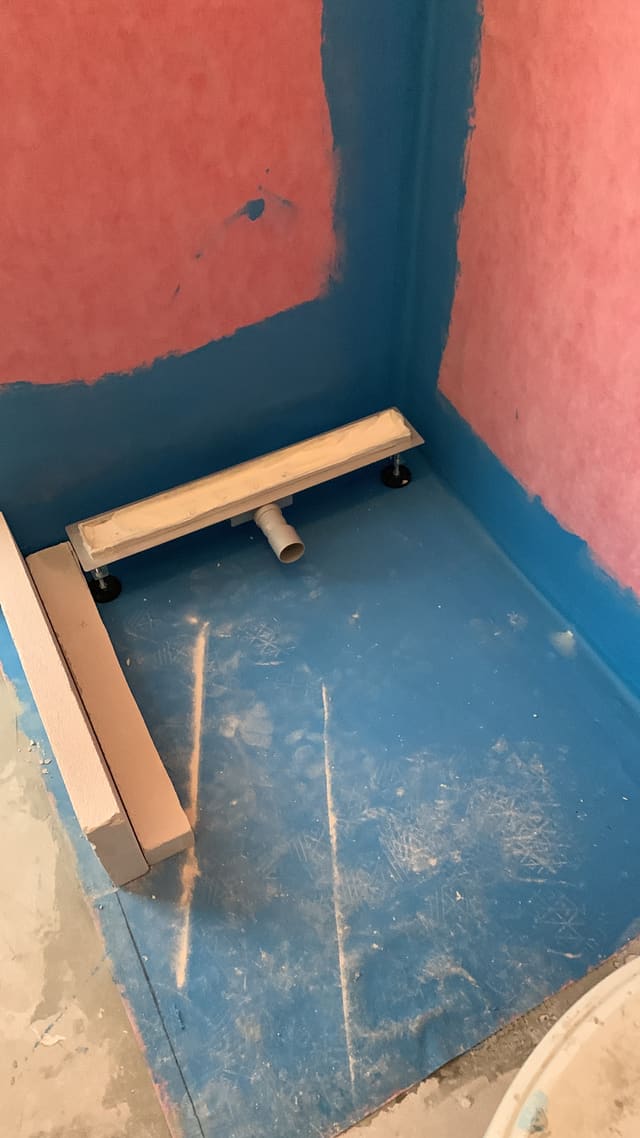 Waterproof tanking membrane applied to a shower corner before tiling