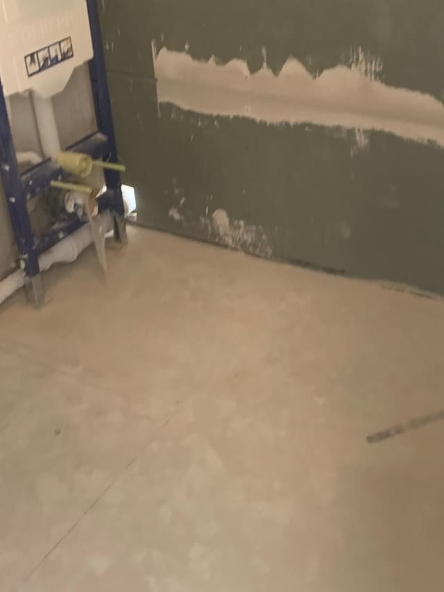Grey tanking membrane applied around a wall-mounted frame ahead of tiling