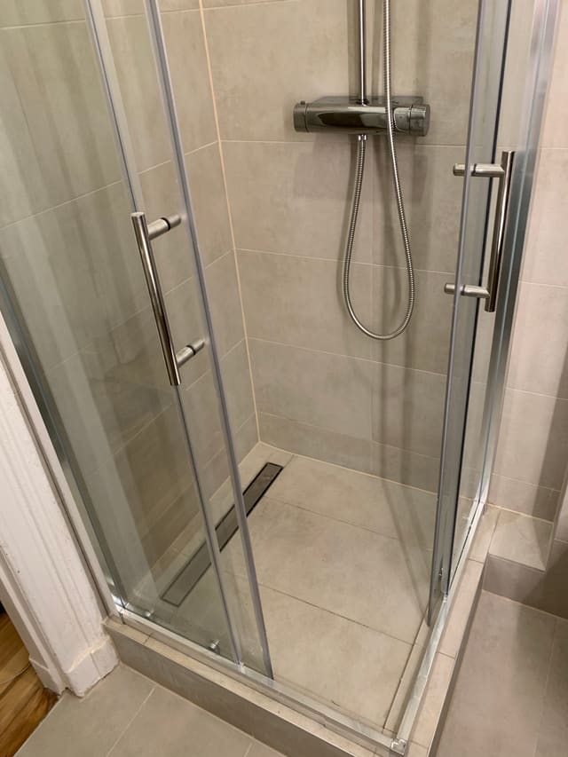Finished corner shower enclosure with glass doors and tiled floor