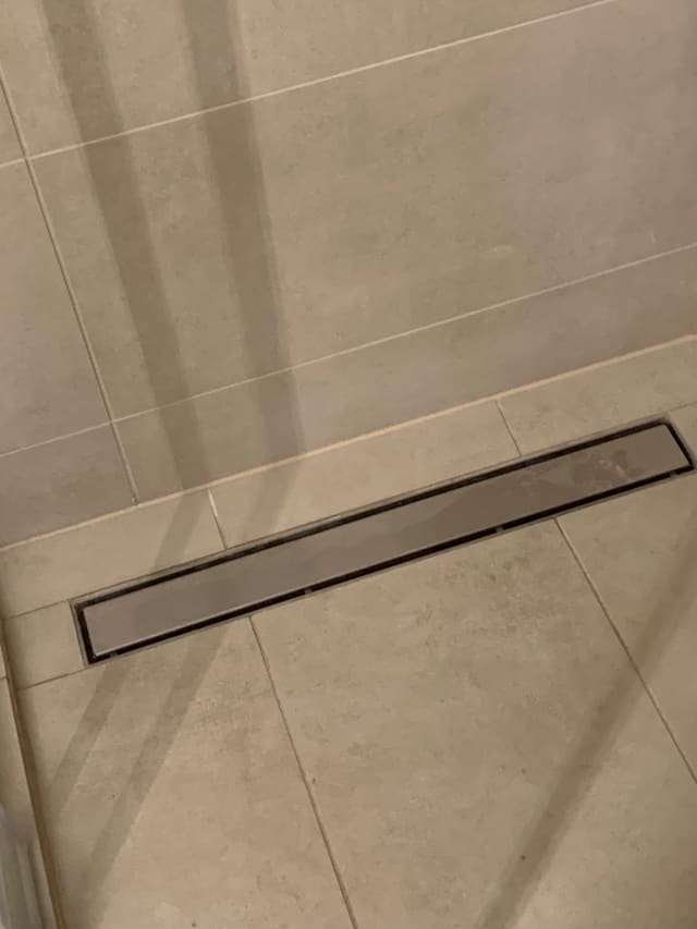 Close-up of a tiled shower floor with a linear drain