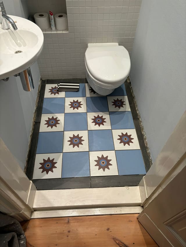 Finished bathroom with blue and white star-pattern tiled floor, toilet and sink