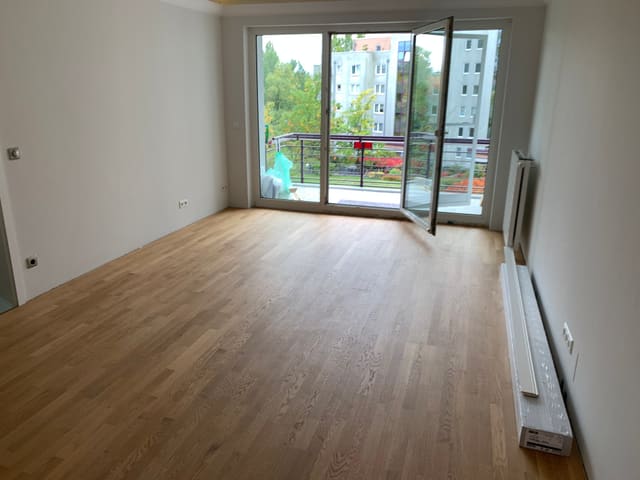 Bright room with new flooring and full-height window onto a balcony