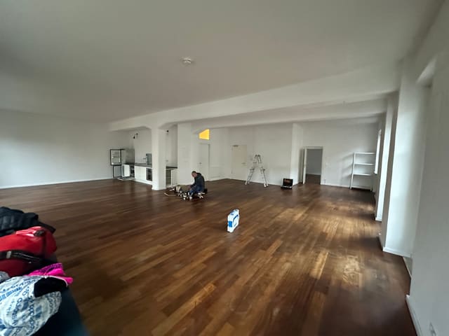 Large open room with dark refinished parquet flooring