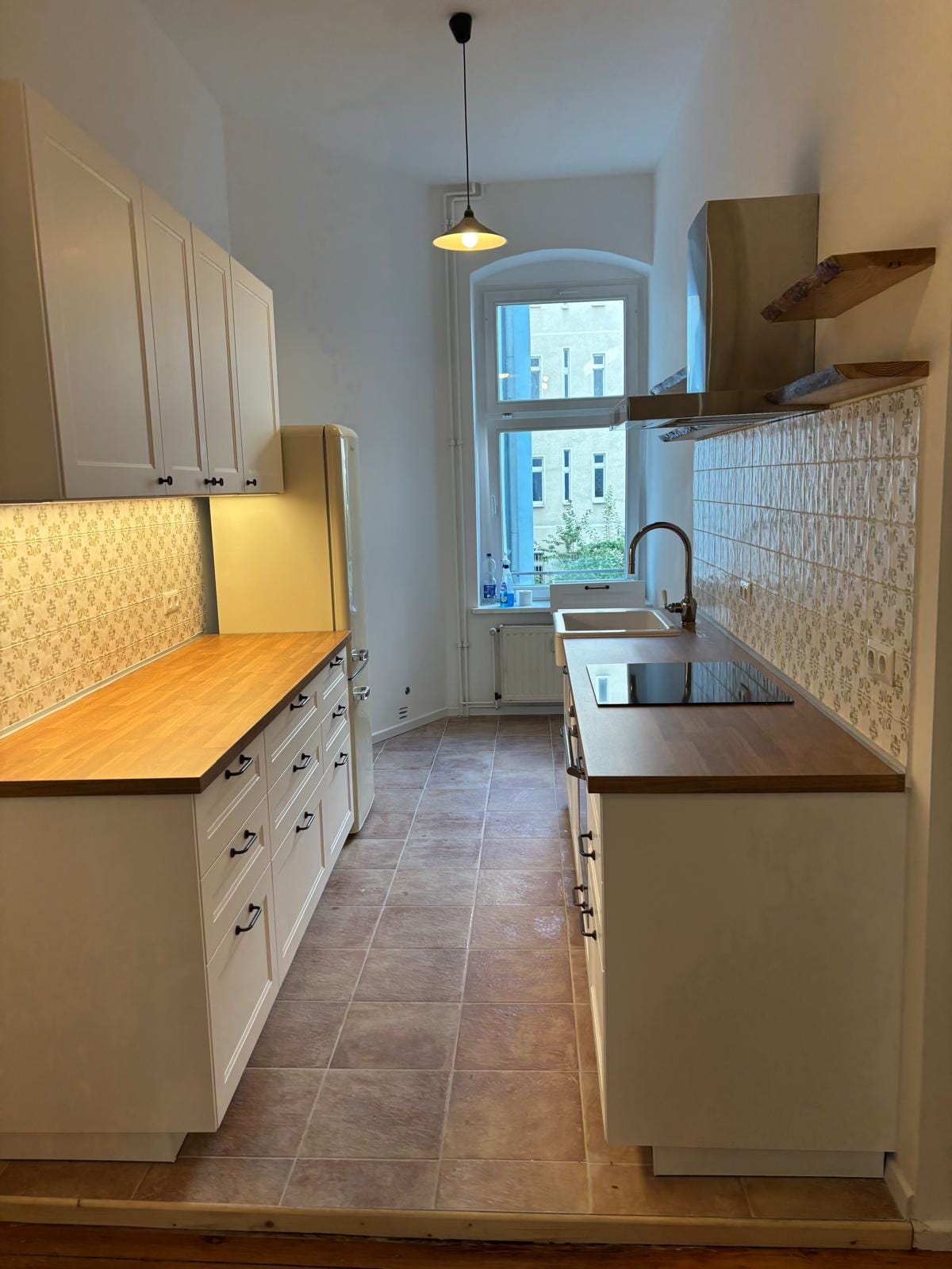 White shaker kitchen with patterned tile splashback and oak worktop, fitted in a Berlin Altbau flat