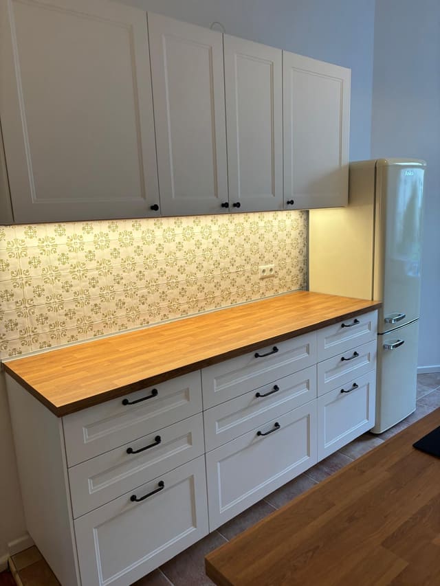 Close-up of fitted kitchen units with under-cabinet lighting and tiled splashback