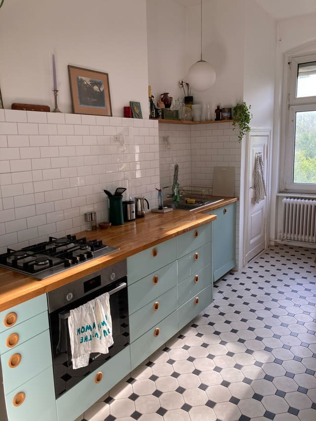 Duck-egg green fitted kitchen with black and white tiled floor