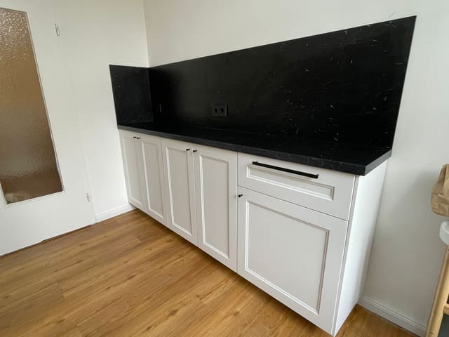 Modern kitchen with black countertop, white cabinets and oak flooring