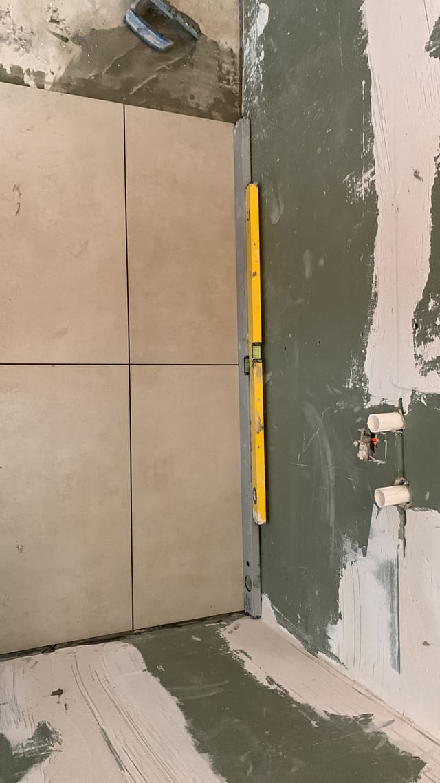 New tiled floor being laid, spirit level checking the fall