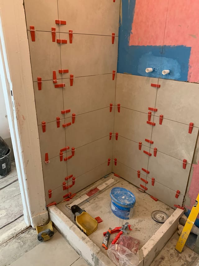Bathroom wall tiling in progress with tile spacers
